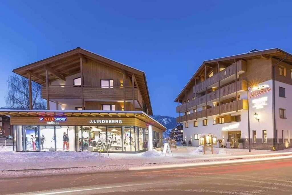 Zwei Chalets im Schnee zur blauen Stunde, alle Fenster beleuchtet