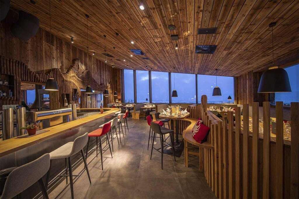 Restaurant mit Holzdecke und Panoramafenstern zur blauen Stunde