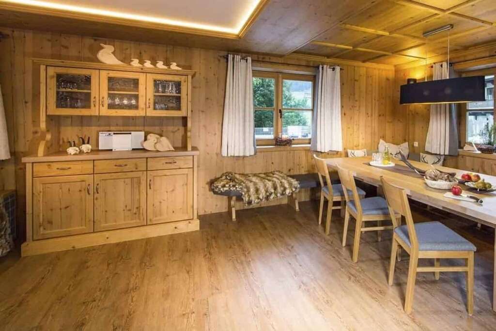 Holzgetäfelter Wohnraum mit Anrichte, Felldecke auf der Bank und gedecktem Esstisch
