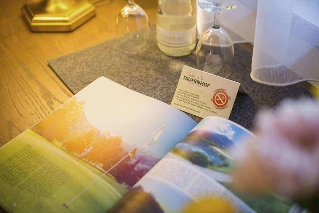 Nahaufnahme eines aufgeschlagenen Prospekts, Wasserflasche, Gläsern und Tischkarte auf Filzunterlage