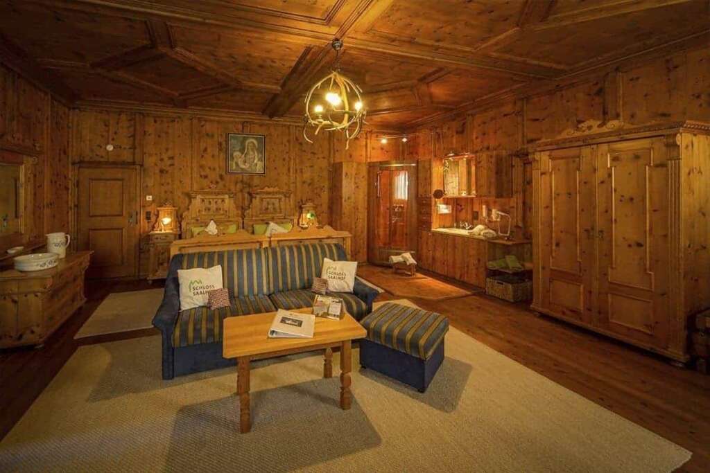 Holzgetäfelte Suite mit Kassettendecke, Bauernschrank, gestreifter Sitzgruppe und Doppelbett