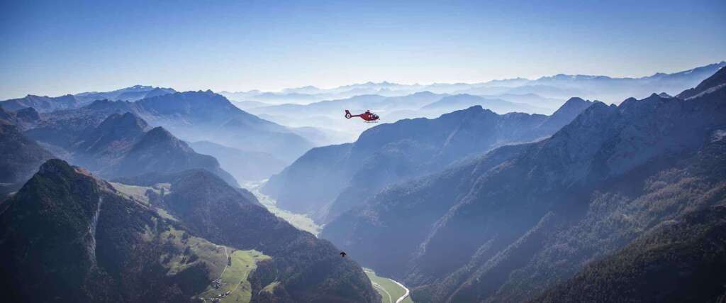 Hubschrauber über einem weiten Gebirgstal im Morgenlicht
