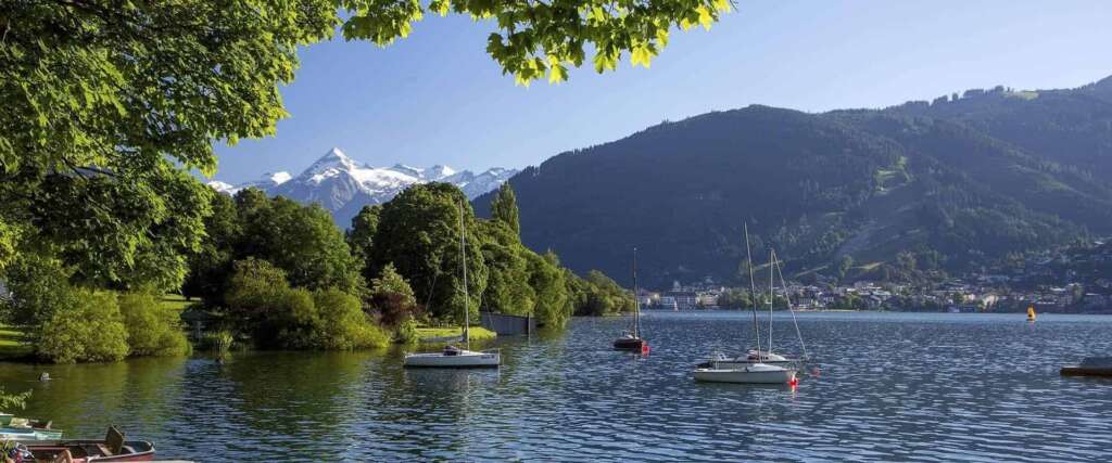 Zeller See mit Segelbooten, dahinter verschneite Berge